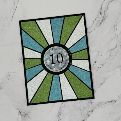 Bright, handmade recovery card with vibrant glitter sections celebrating a decade of sobriety.
