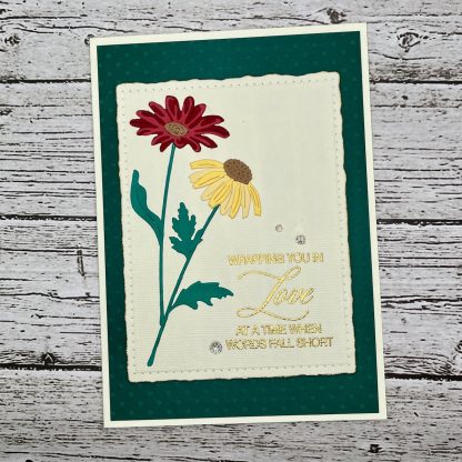Handmade sympathy card with layered red and yellow flowers, elegant sentiment reading “wrapping you in love at a time when words fall short” on a subtly dotted dark green background.