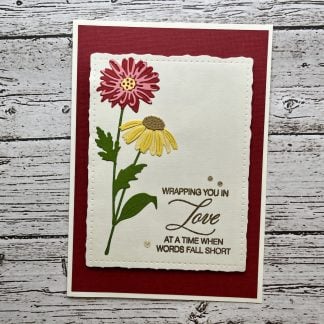 Handmade sympathy card with layered red and yellow flowers, elegant sentiment reading “Wrapping you in love at a time when words fall short.”